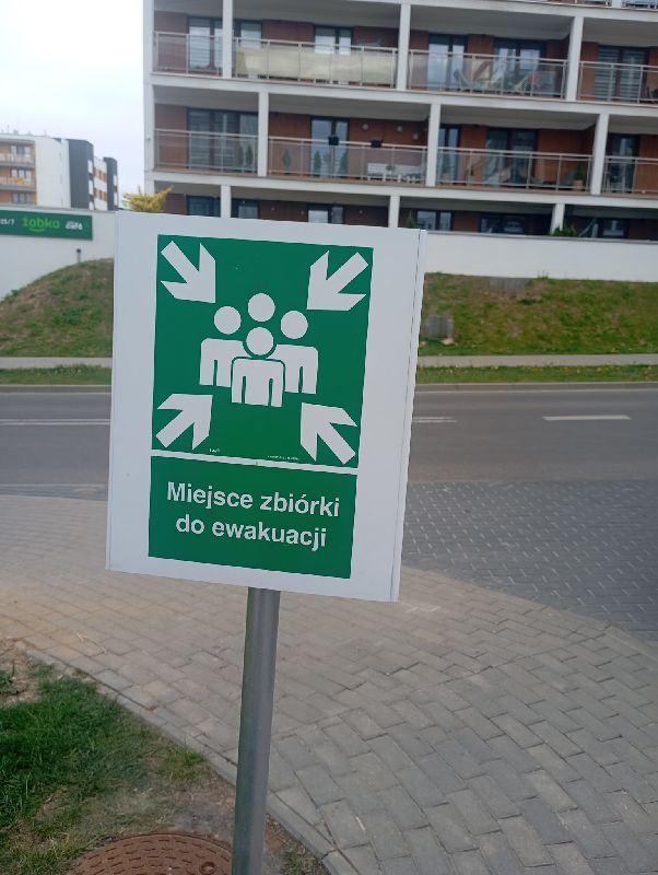 Tablica miejsce zbiórki do ewakuacji jako symbol wielkiej ucieczki